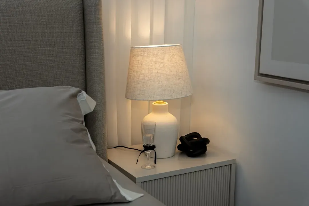 Modern bedroom air purifier placement on nightstand with proper 12-inch wall clearance and mid-height positioning for optimal