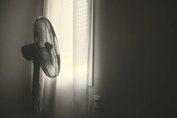 Modern air purifier in bedroom corner with closed windows showing hazy outdoor wildfire smoke versus clean indoor air